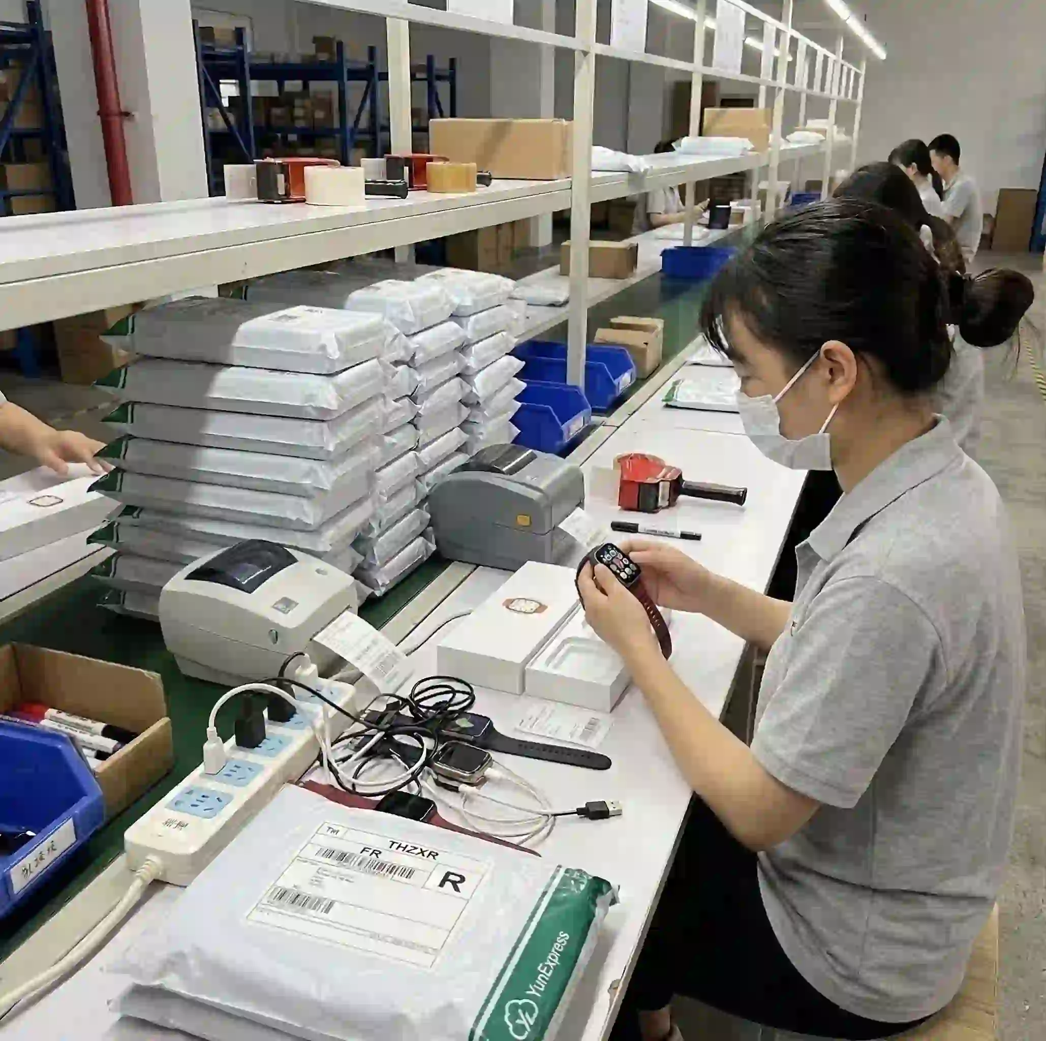 Warehouse staff testing an electronic device before packing and dispatch