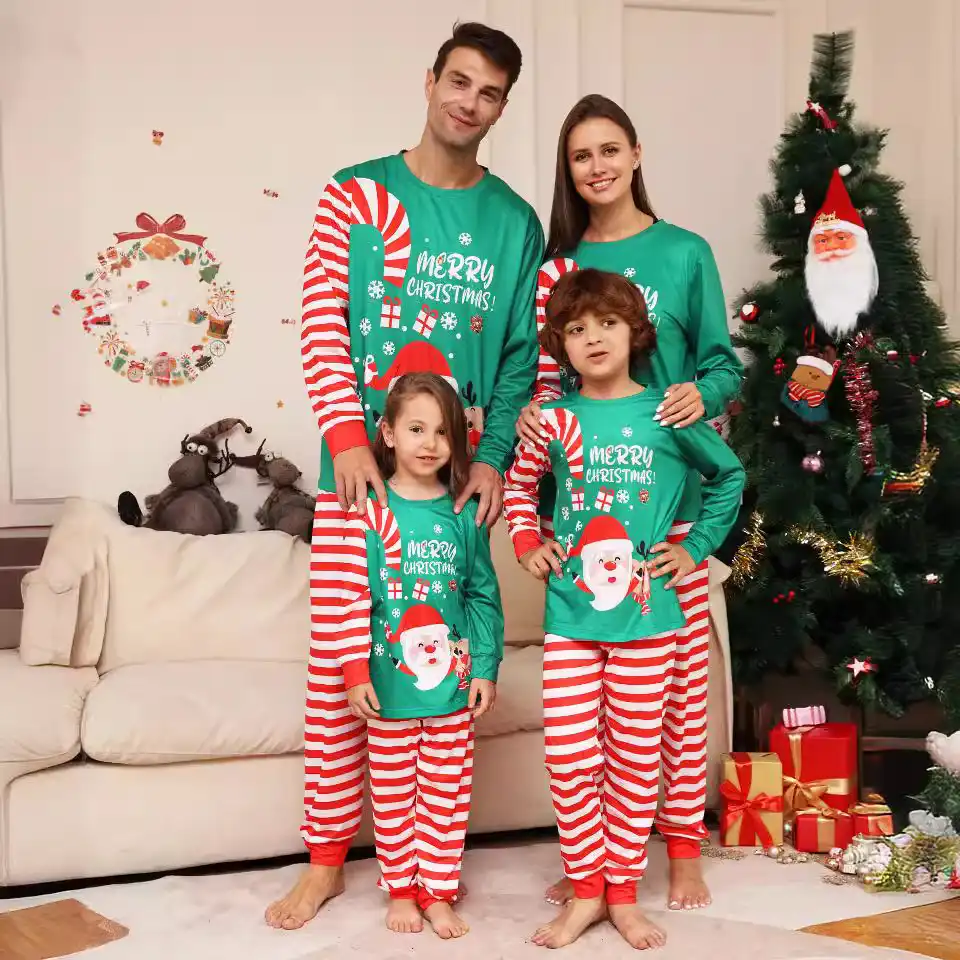 Family wearing matching green and red Christmas pajamas beside a decorated tree