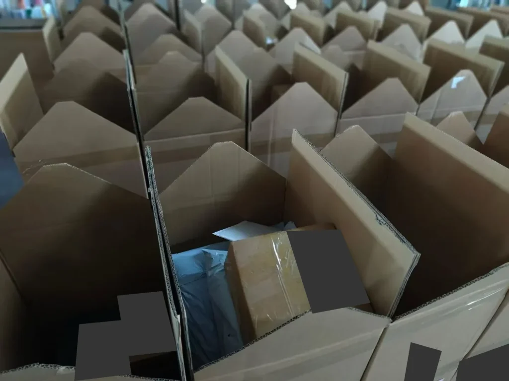 Open cartons holding packed parcels, with shipping labels covered for privacy
